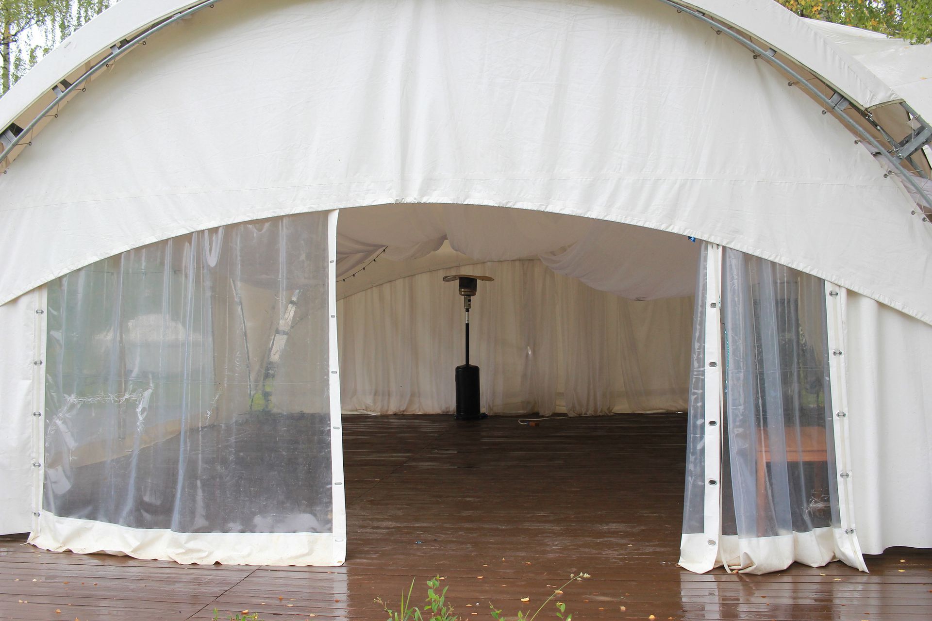 White tent entrance with clear plastic sides, interior with dark floor, a heater is inside.