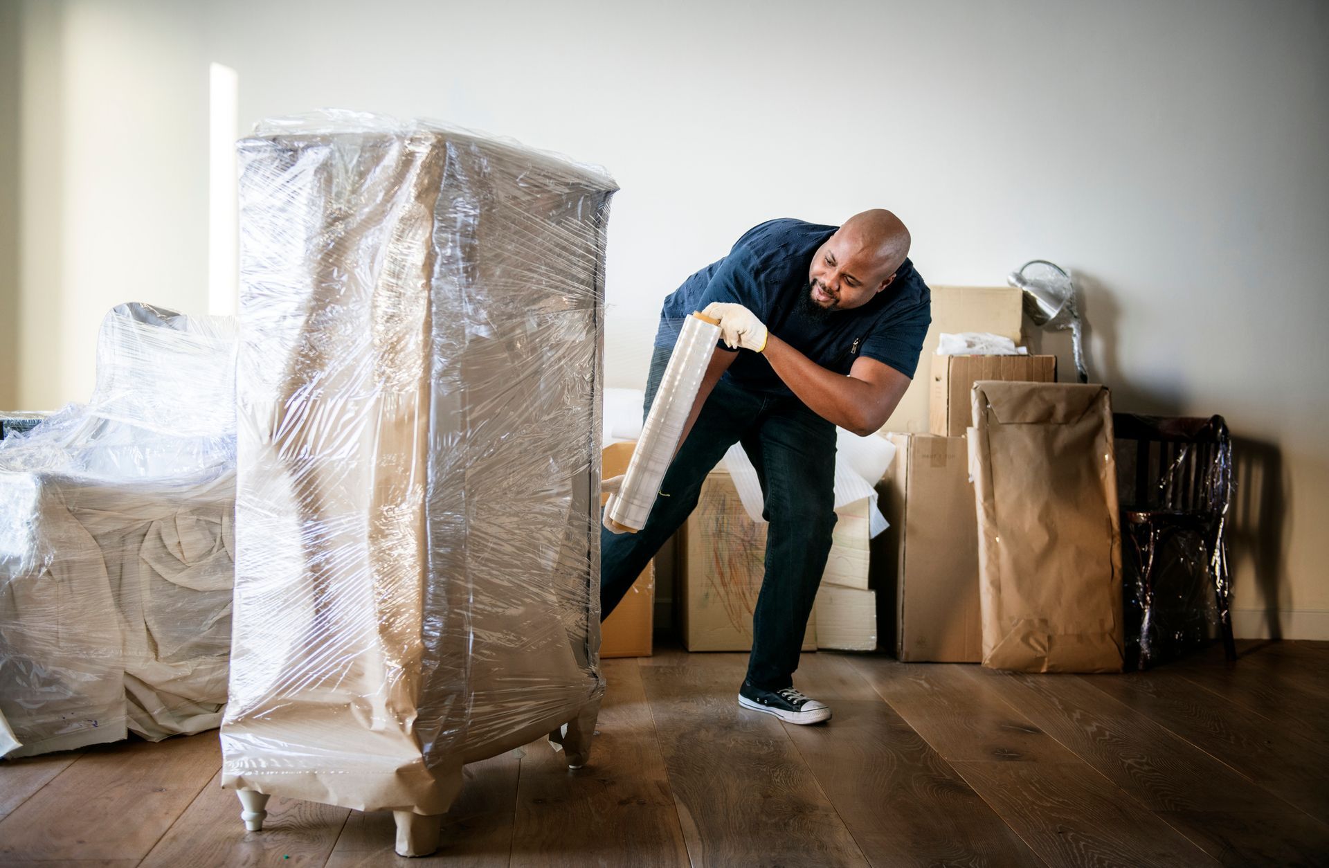 Man wrapping furniture in protective wrap during a move.