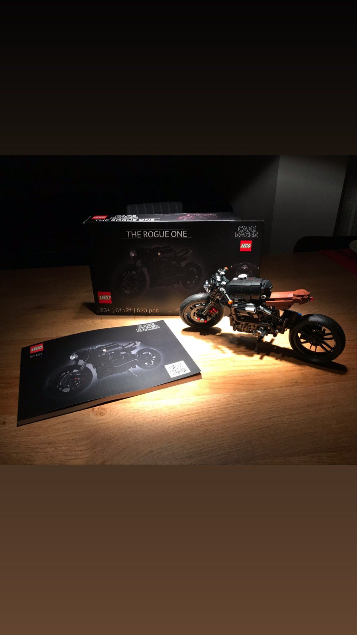 A motorcycle is sitting on top of a wooden table next to a box.
