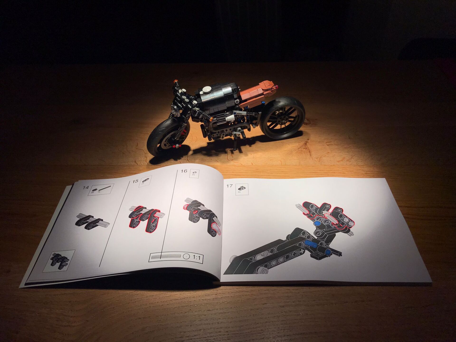 A toy motorcycle is sitting next to an open instruction book