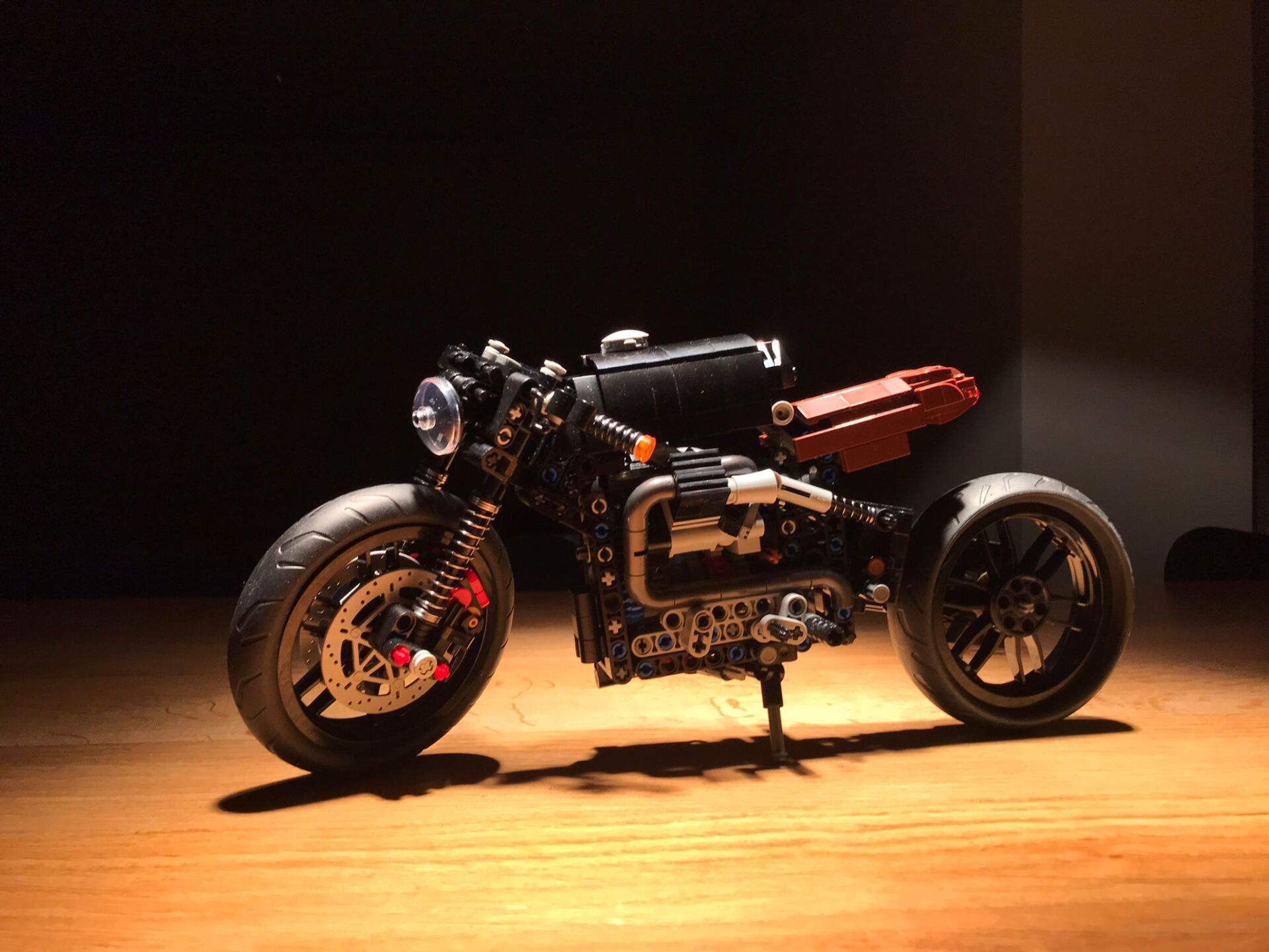 A motorcycle is sitting on a wooden floor in a dark room.