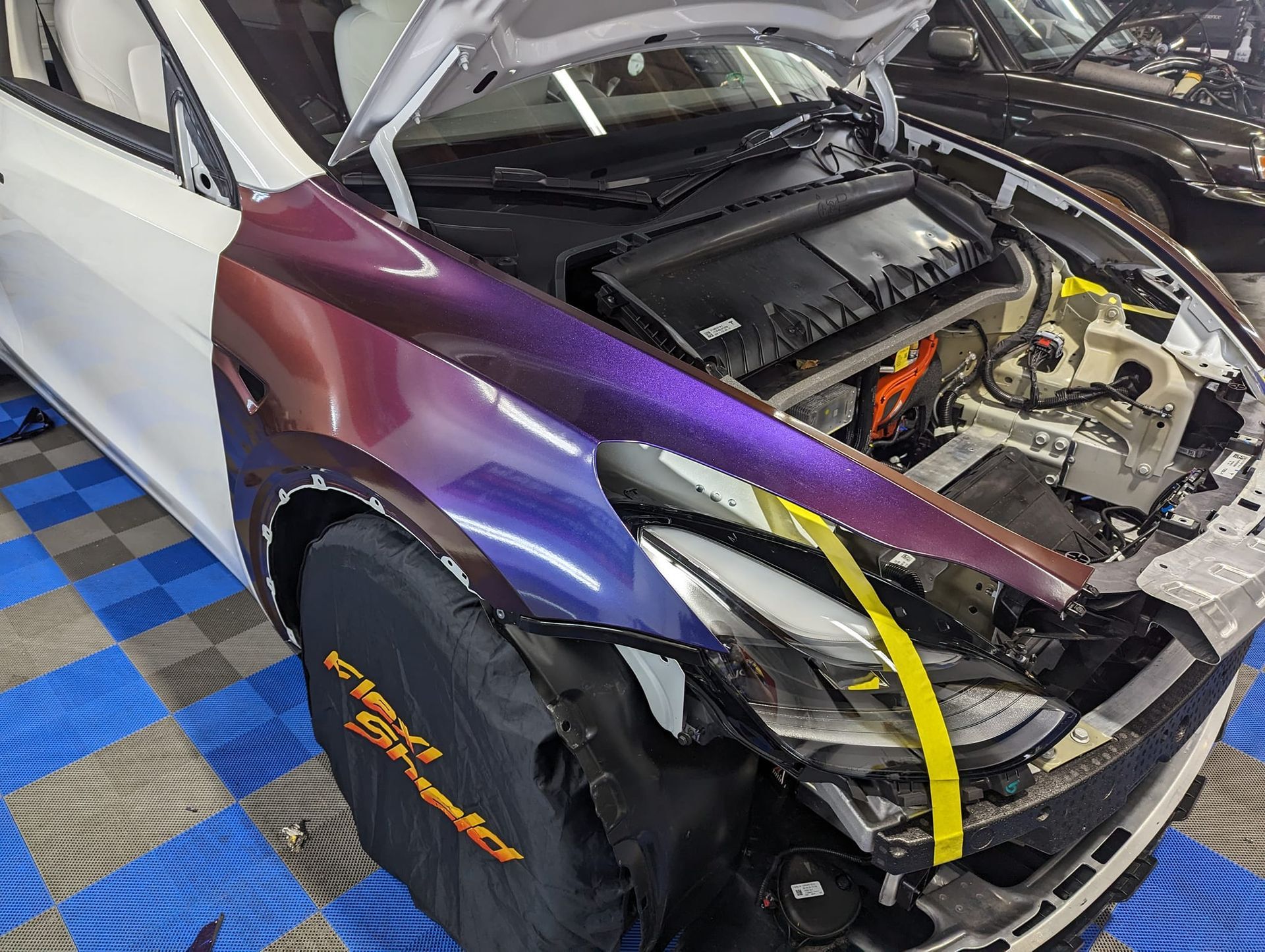 A purple and white car with the hood open is sitting on a tiled floor.
