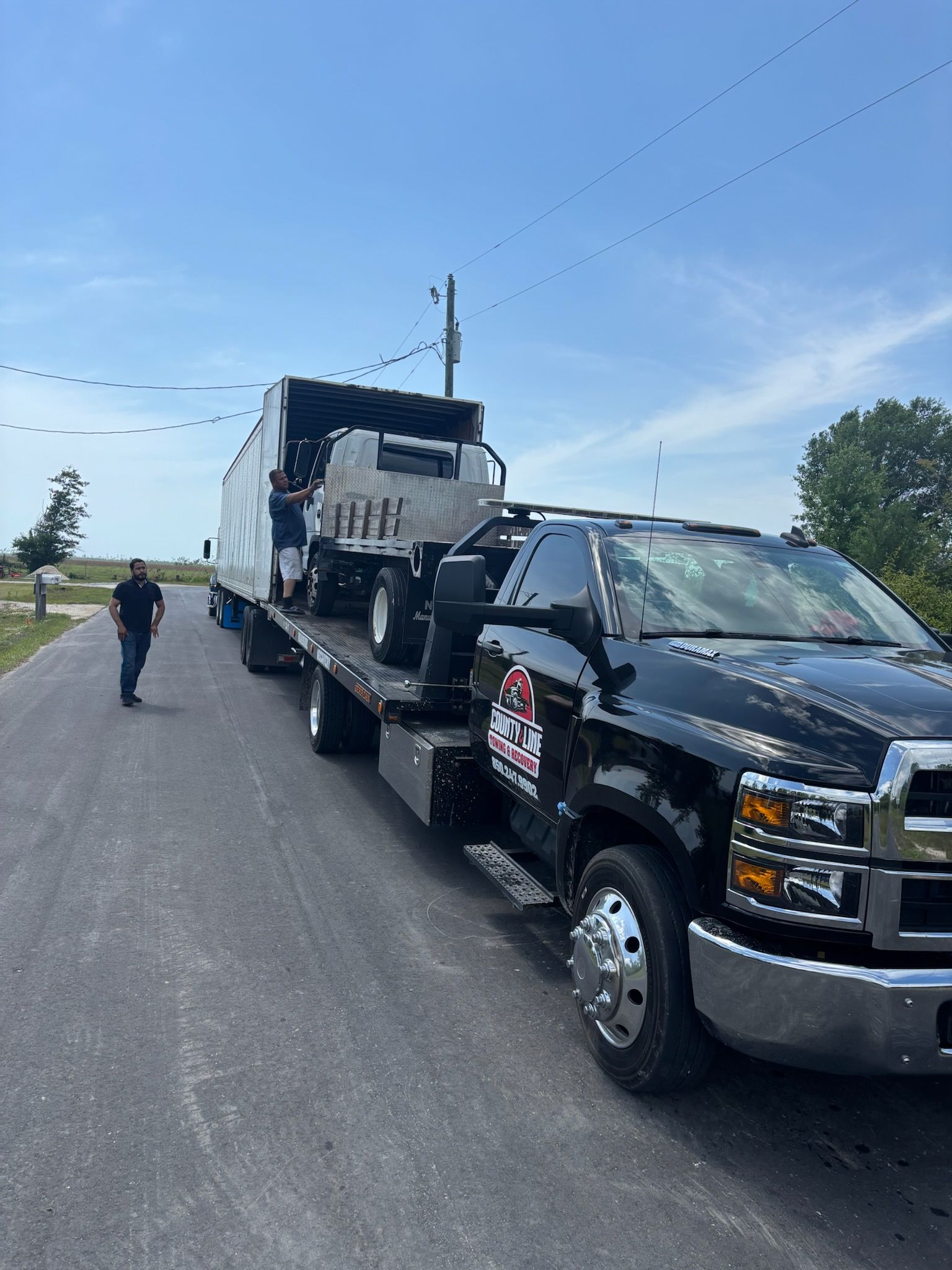 Black tow truck transporting a red aerial lift platform; 