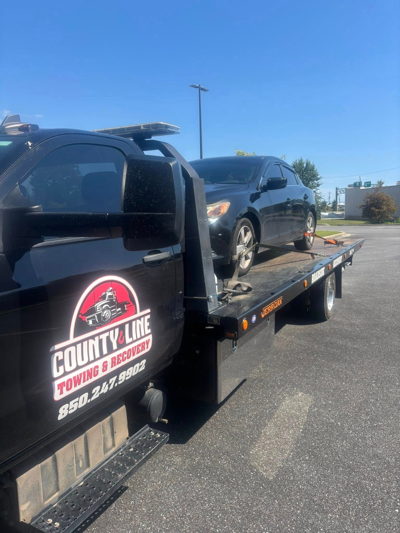 Black car on a flatbed tow truck with