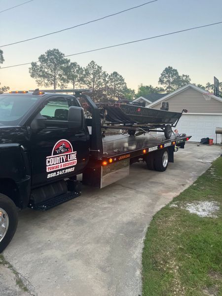 Black County Line truck on a driveway with a lifted dump bed, near a house with a garage.