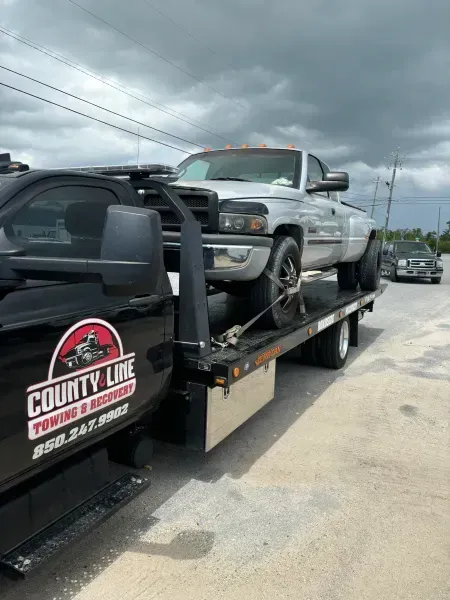 Silver pickup truck being towed by a County Line towing truck.