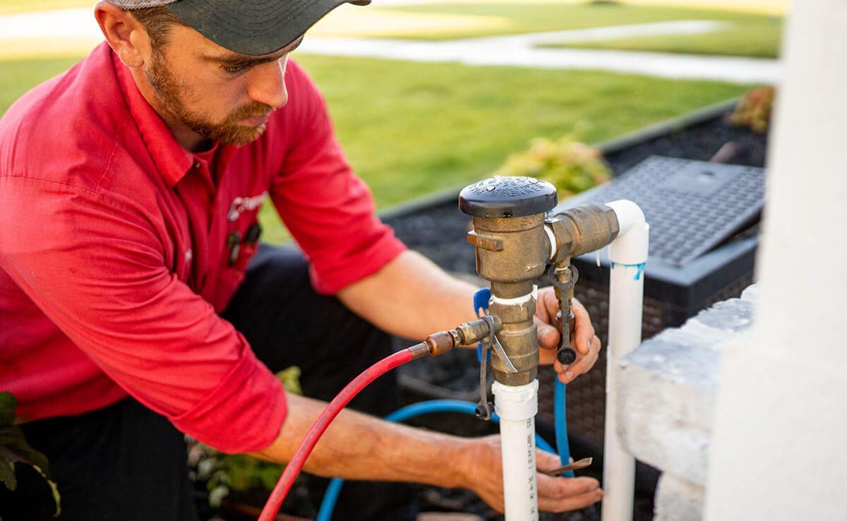 Man in red shirt adjusting outdoor sprinkler system, close up.