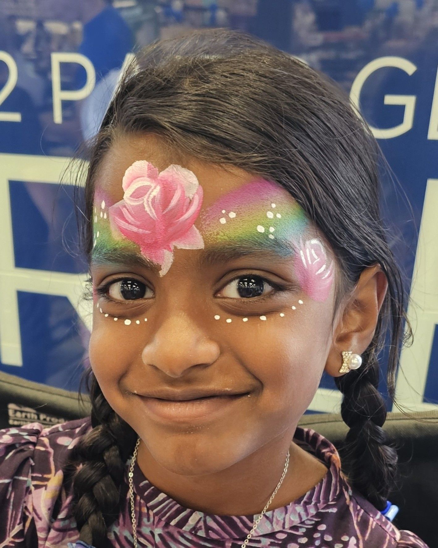 Pink flower and rainbow design on forehead. 