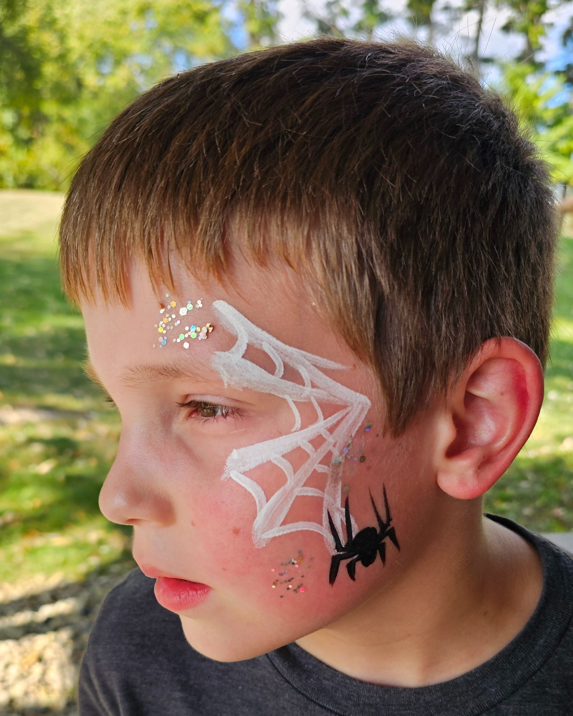 Half face paint of a white spider web and black spider. 