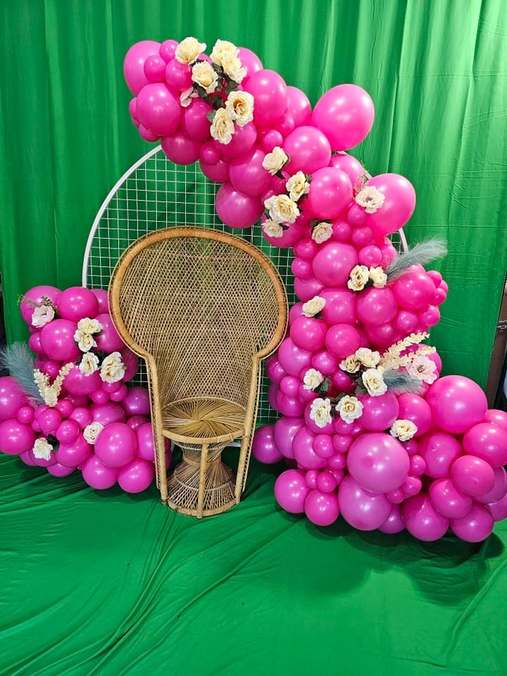 Hot pink organic garland with mini garland on metal circle frame and artificial roses. Wicker chair available for rent.