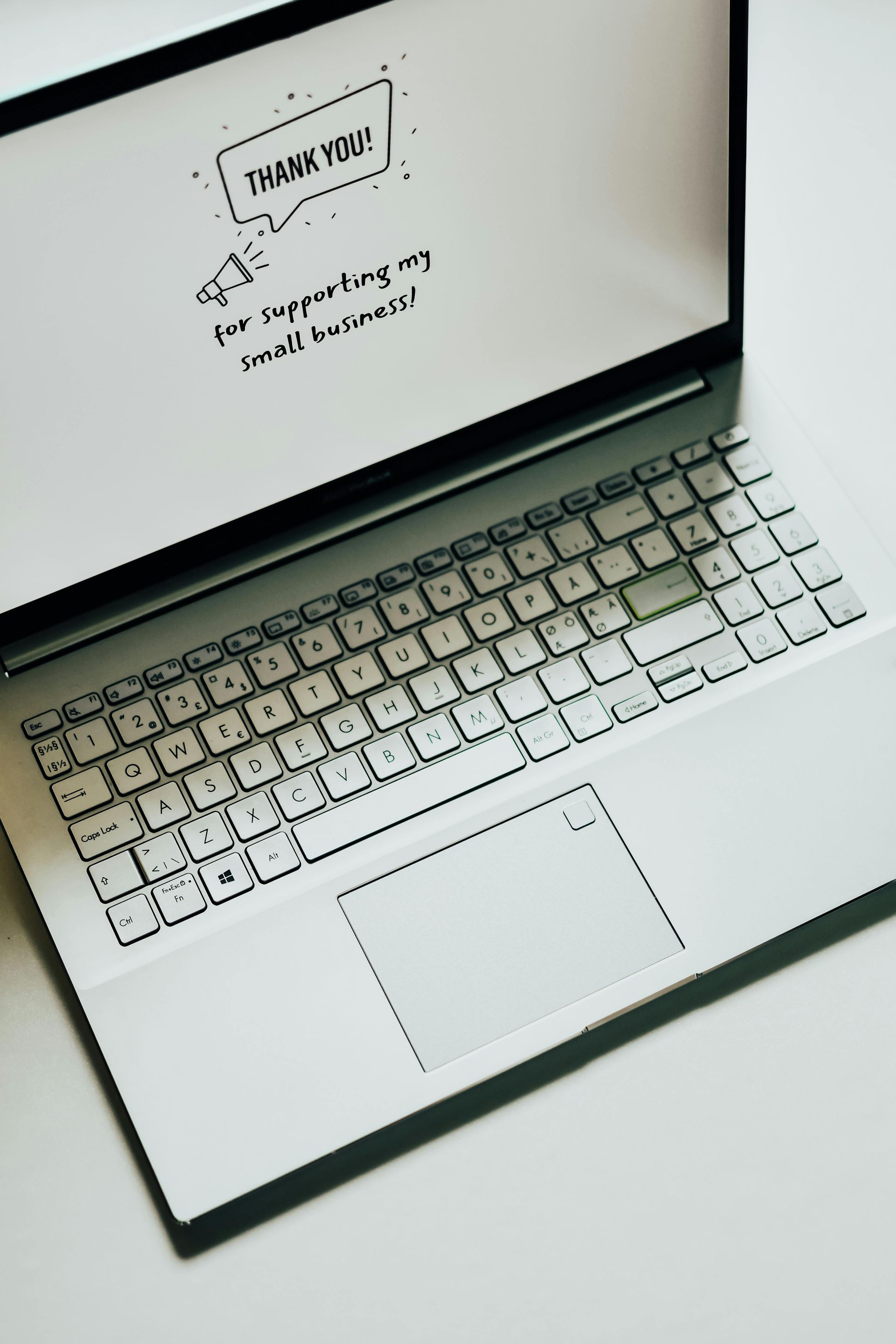An elderly couple smiling while looking at a tablet together on a sofa.