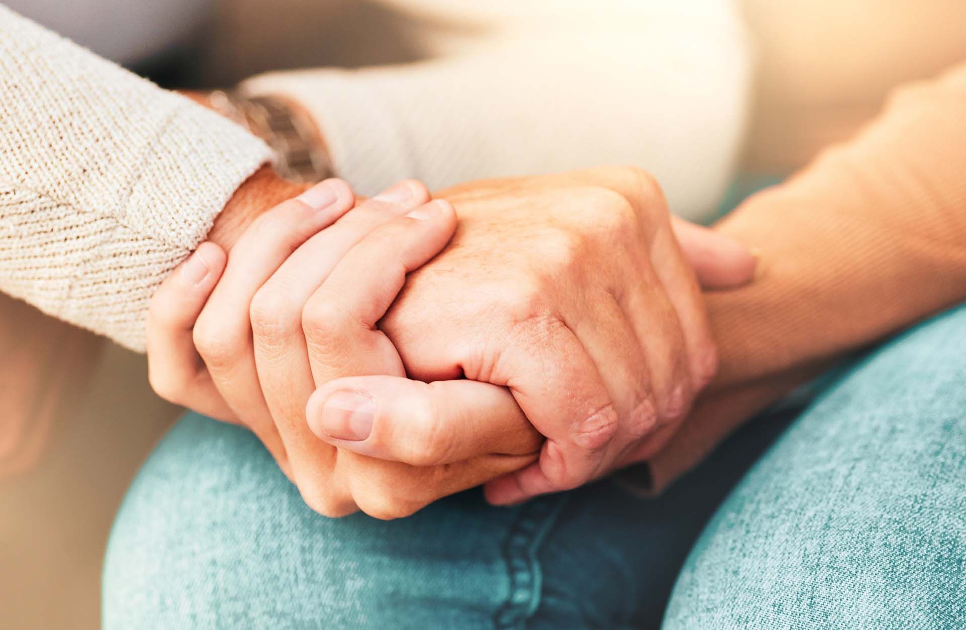 Two hands clasped together, offering comfort and support.