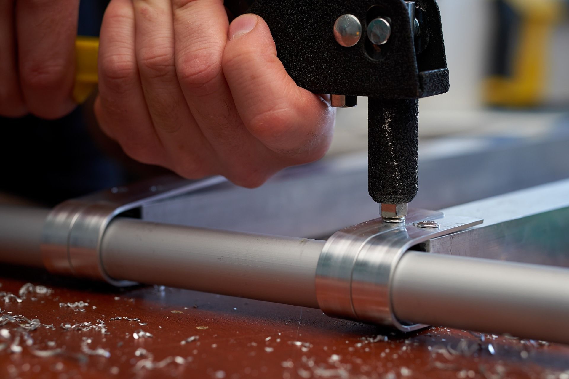 A person is cutting a metal pipe with a tool.