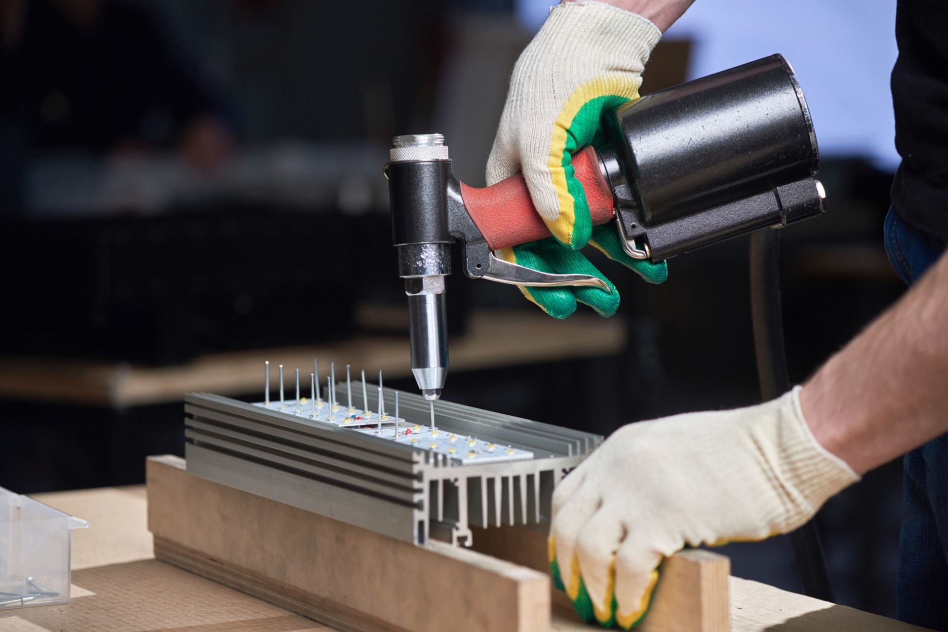 A man is using an air drill to drill a hole in a piece of metal.