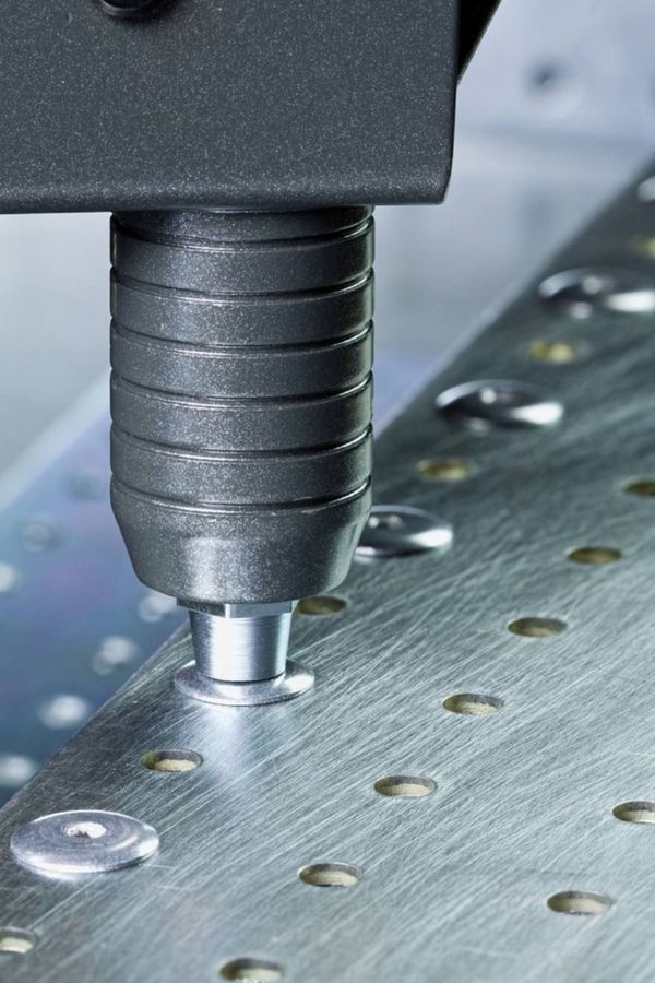 A machine is cutting a piece of metal with holes in it.