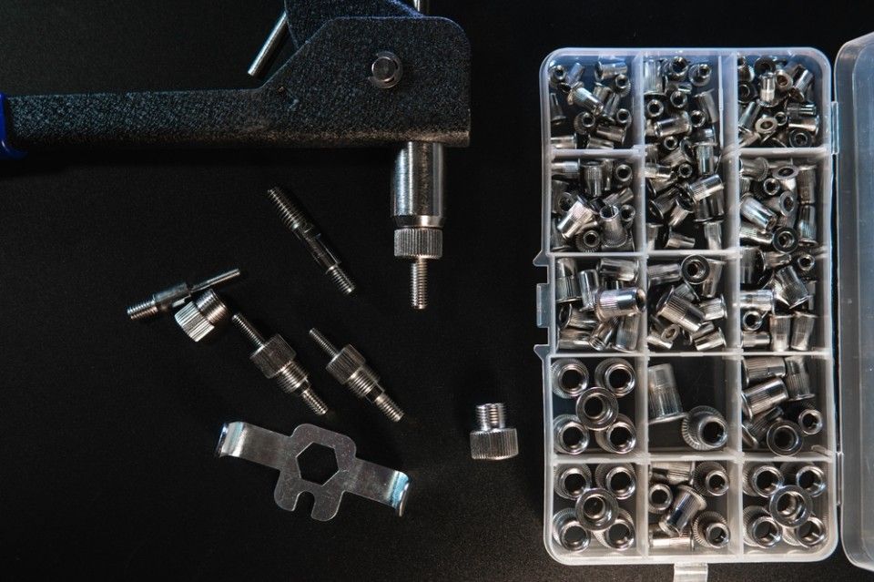 A box of nuts and bolts next to a tool