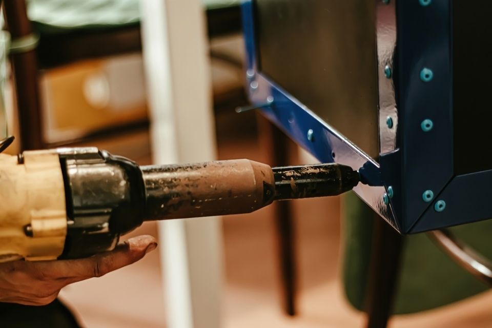 A person is using a drill to drill a hole in a piece of metal.