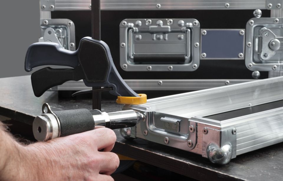 A person is using a clamp to fix a case on a table.