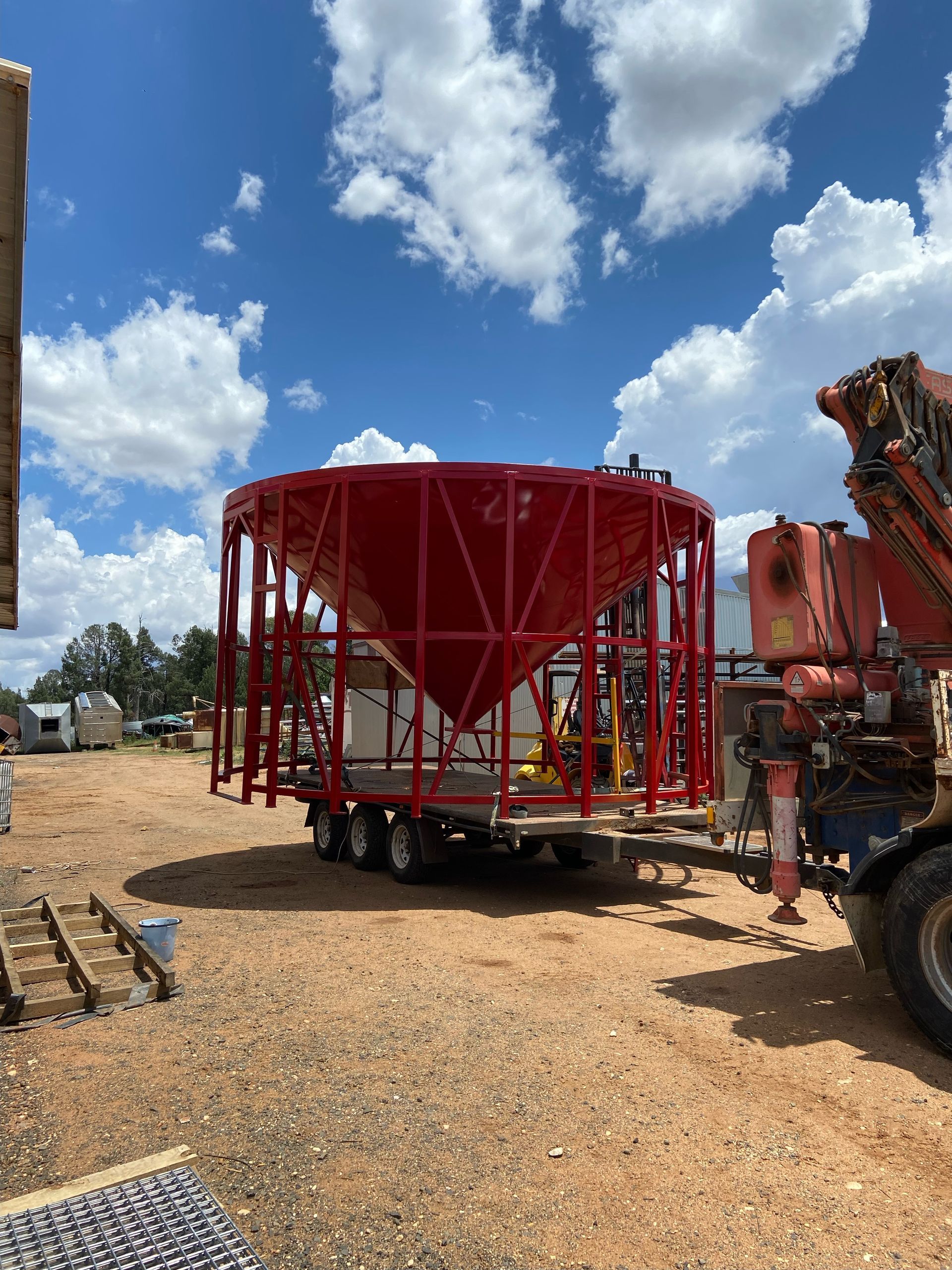 A Large Red Tank is Sitting on Top of a Trailer in a Dirt Field — Welders In Gilgandra, NSW