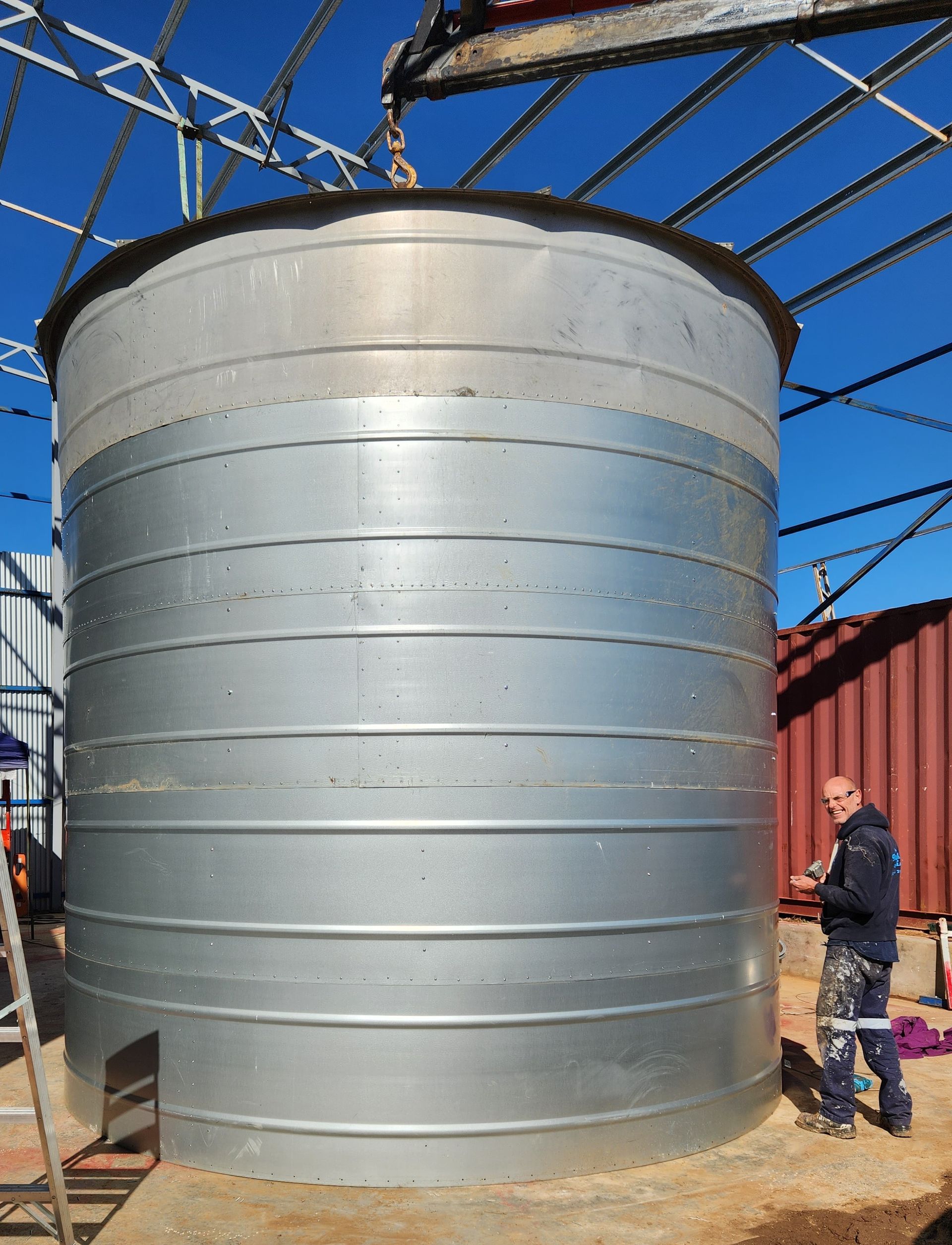 A Man is Standing in Front of a Large Metal Silo — Welders In Gilgandra, NSW