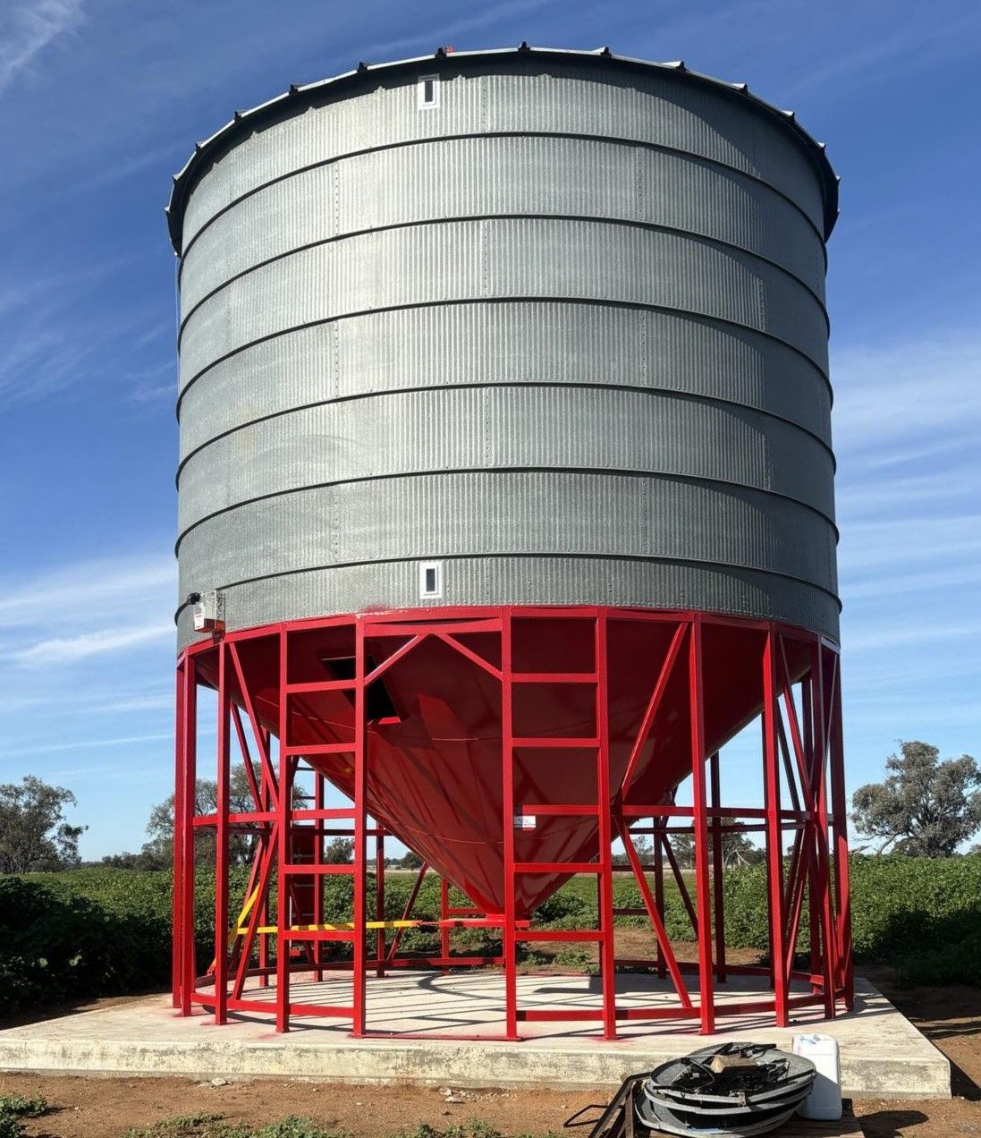 A Large Metal Silo With a Red Base and Stairs — Welders In Gilgandra, NSW