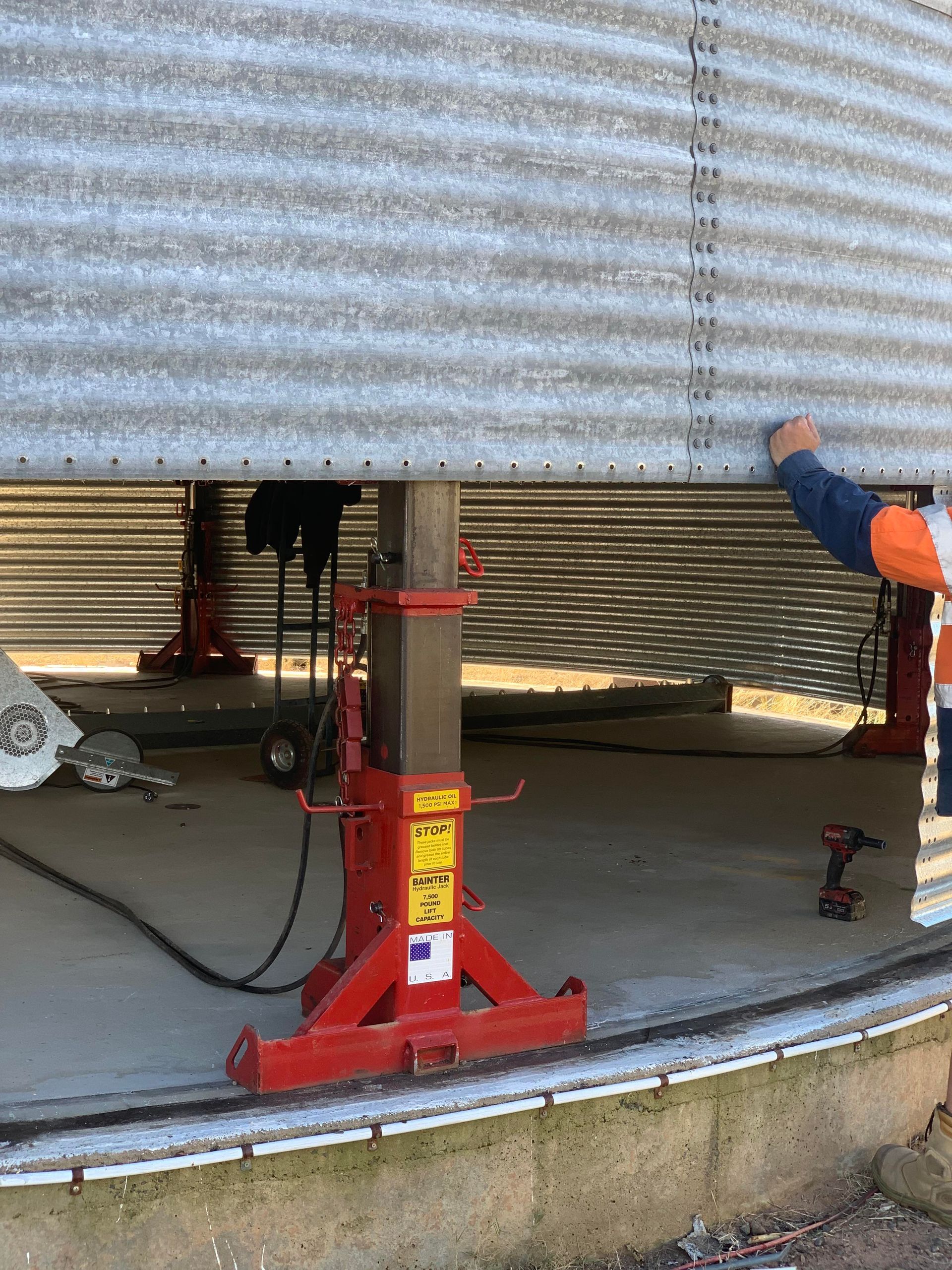 A Man is Working on a Silo With a Red Jack — Welders In Gilgandra, NSW
