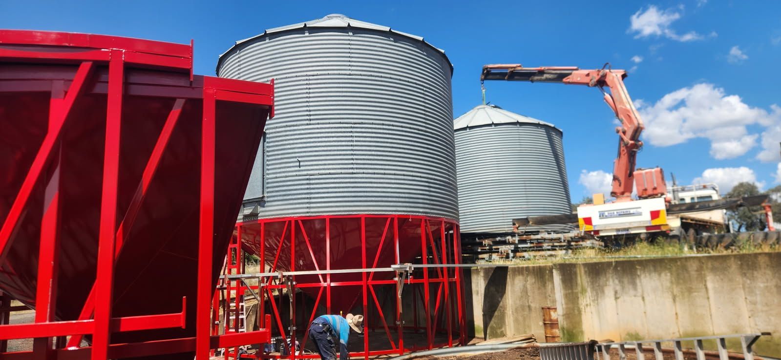 A Man is Standing in Front of a Row of Silos With a Crane in the Background — Welders In Gilgandra, NSW