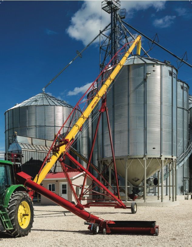 A Green Tractor is Parked in Front of a Grain Silo — Welders In Gilgandra, NSW