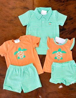 A group of baby clothes with turtles on them are sitting on a table.