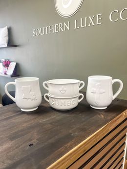 Three white mugs are stacked on top of each other on a wooden table.