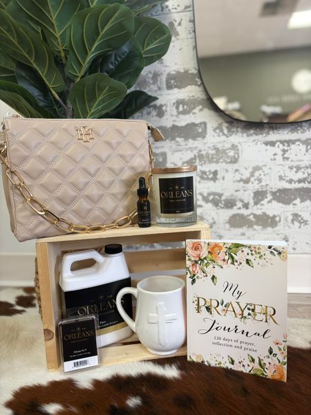 A purse , mug , candle , and a prayer journal are sitting on top of a wooden box.