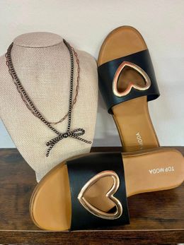 A pair of black sandals with a heart cut out on the side.