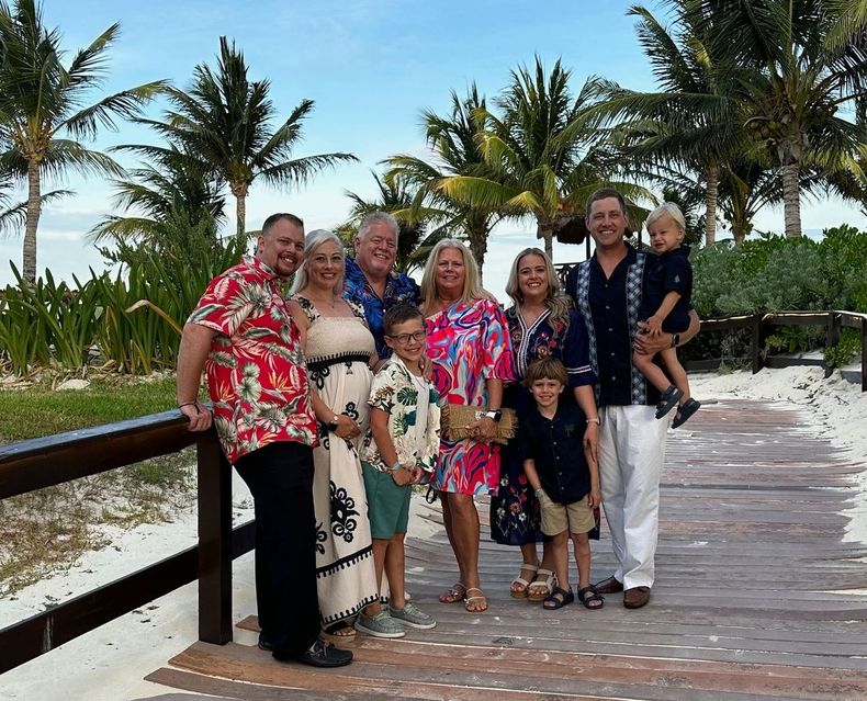 A large family is posing for a picture on a beach.