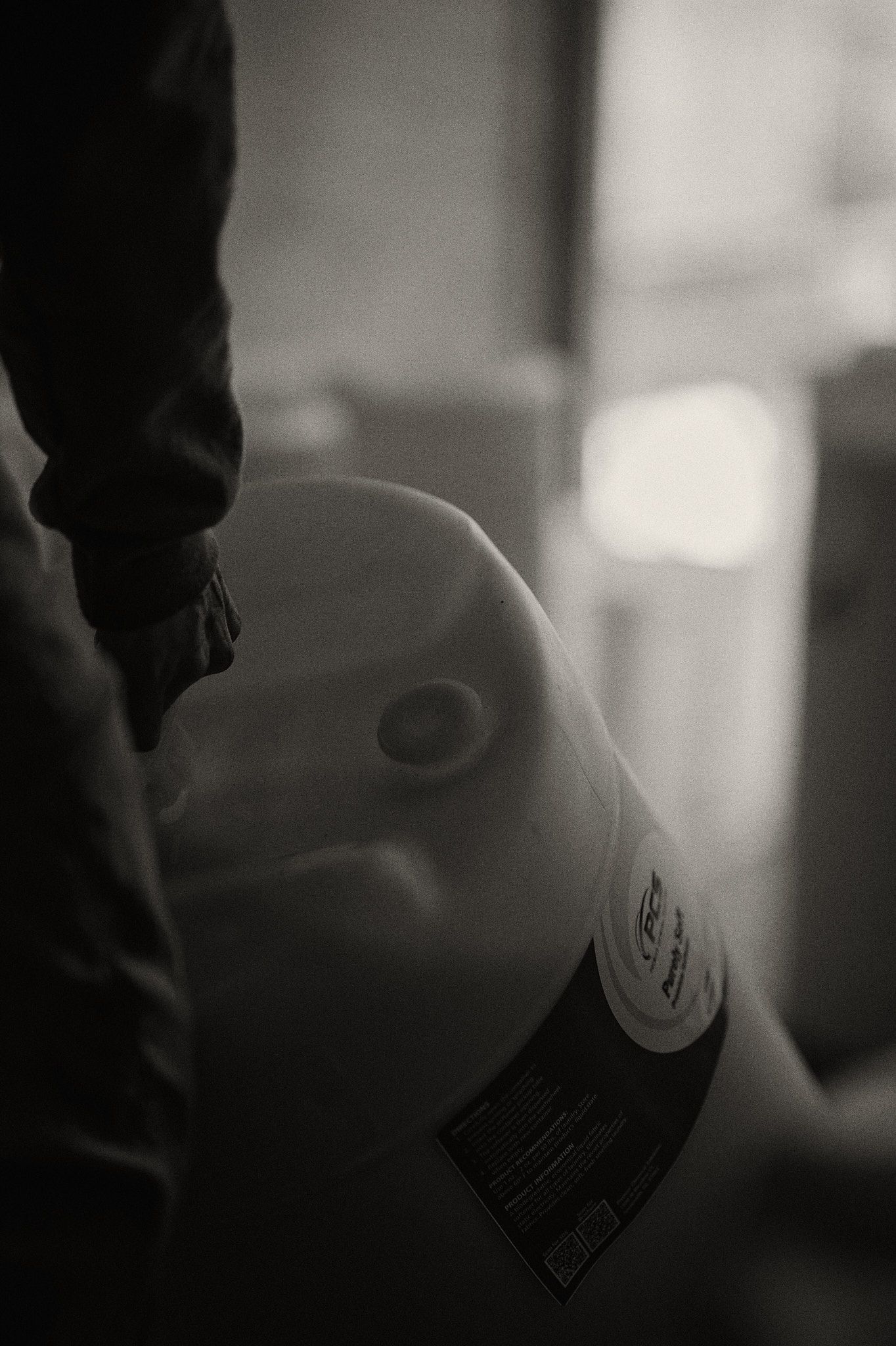 Person holding a large, packaged turkey; black and white.