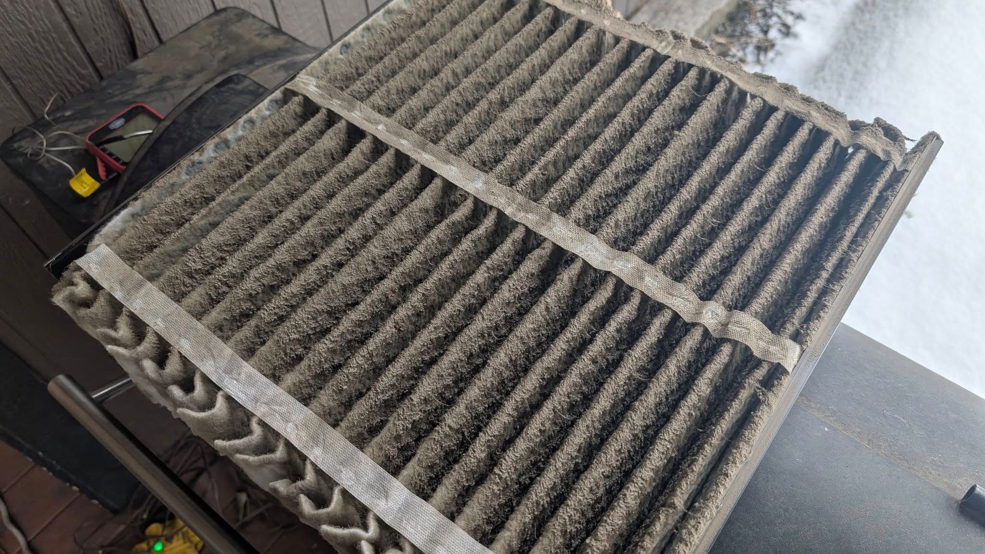A dirty air filter is sitting on top of a wooden table.