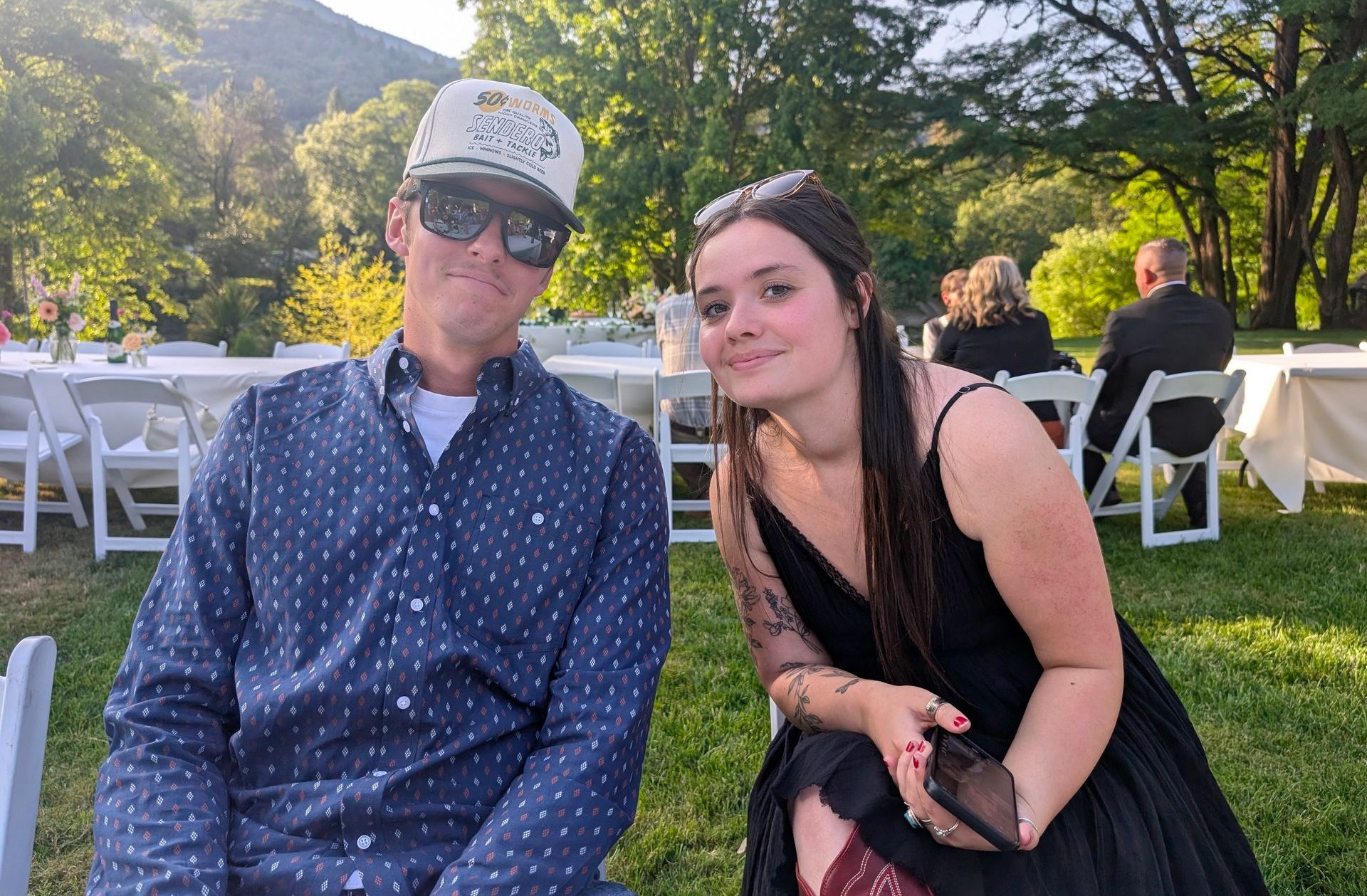 A man and a woman are sitting next to each other in a field.