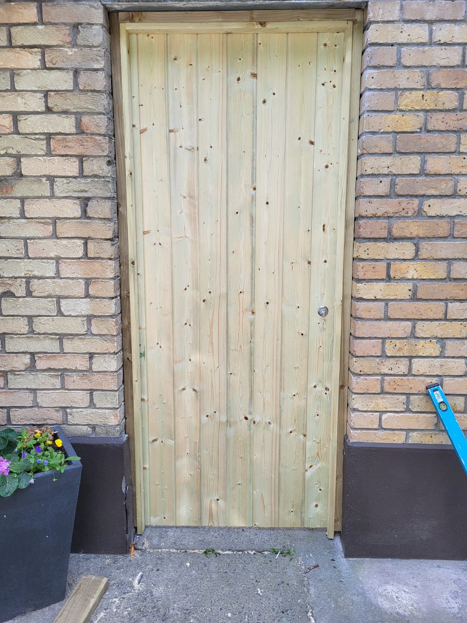 A wooden door is sitting in front of a brick wall.