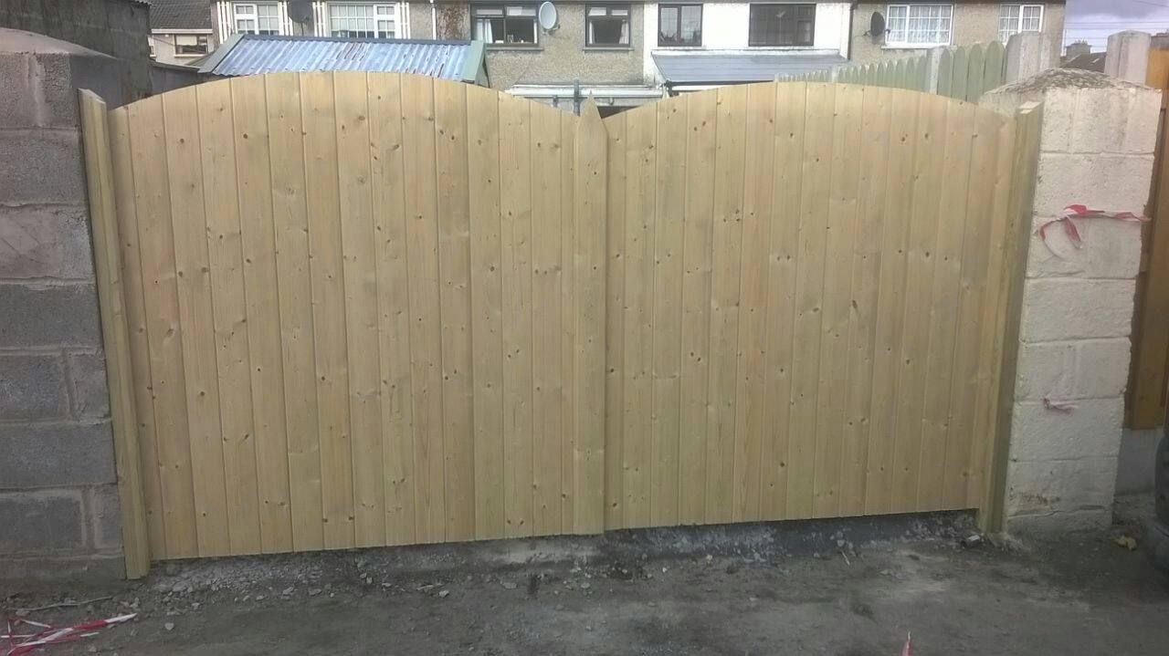 A wooden gate is sitting next to a brick wall.