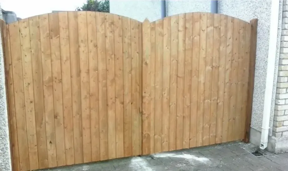 A wooden fence is sitting in front of a brick building.