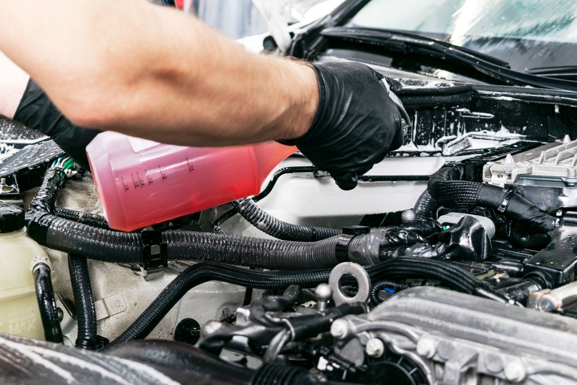 A person is pouring liquid into a car engine.