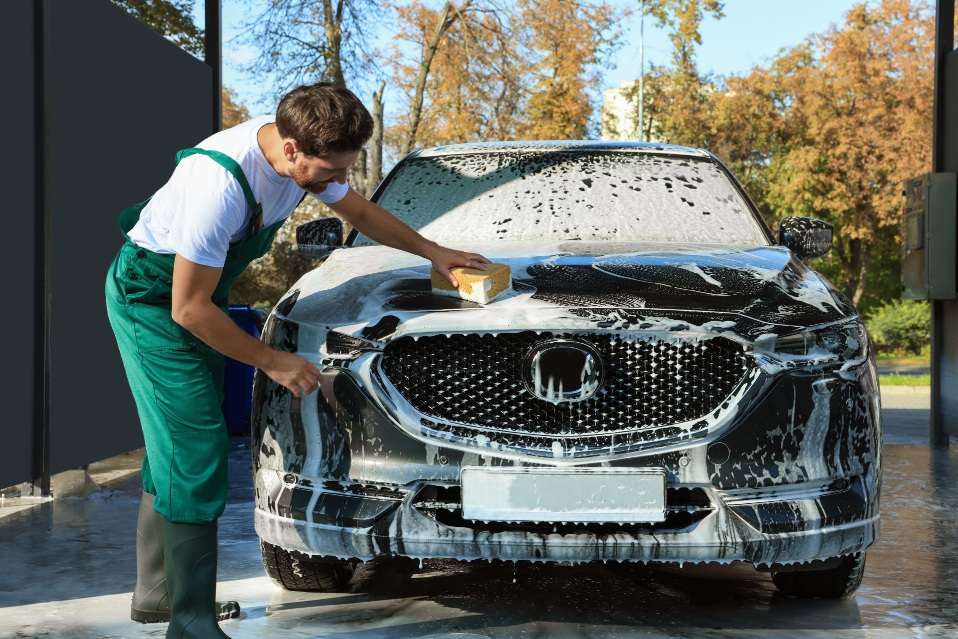 A man is washing a car with a sponge at a car wash.