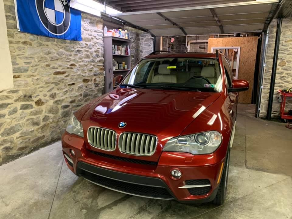 A red bmw x5 is parked in a garage.