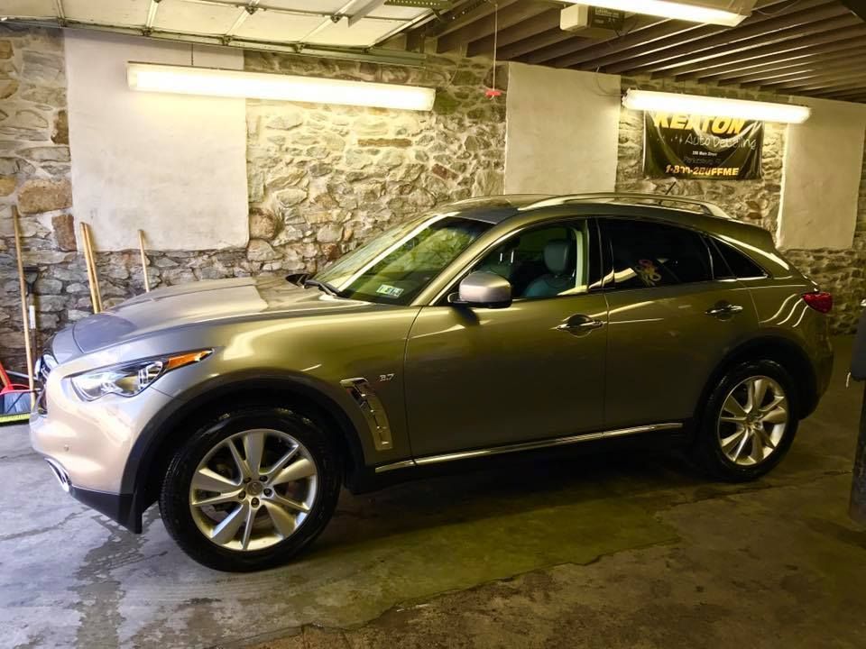 A silver car is parked in a garage next to a stone wall.