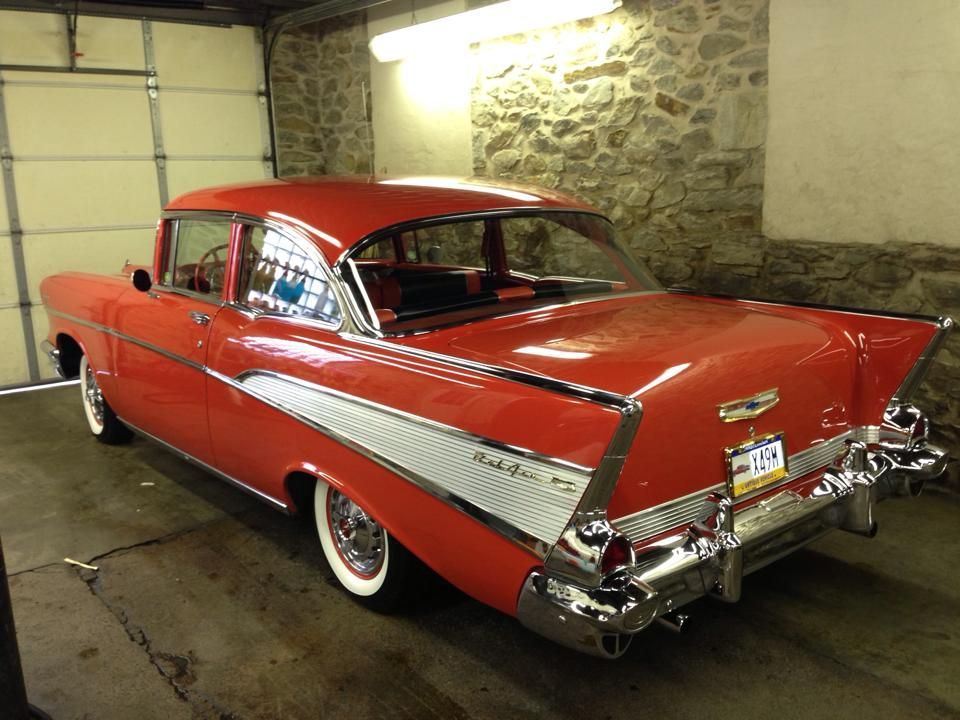 A red car with white tires is parked in a garage