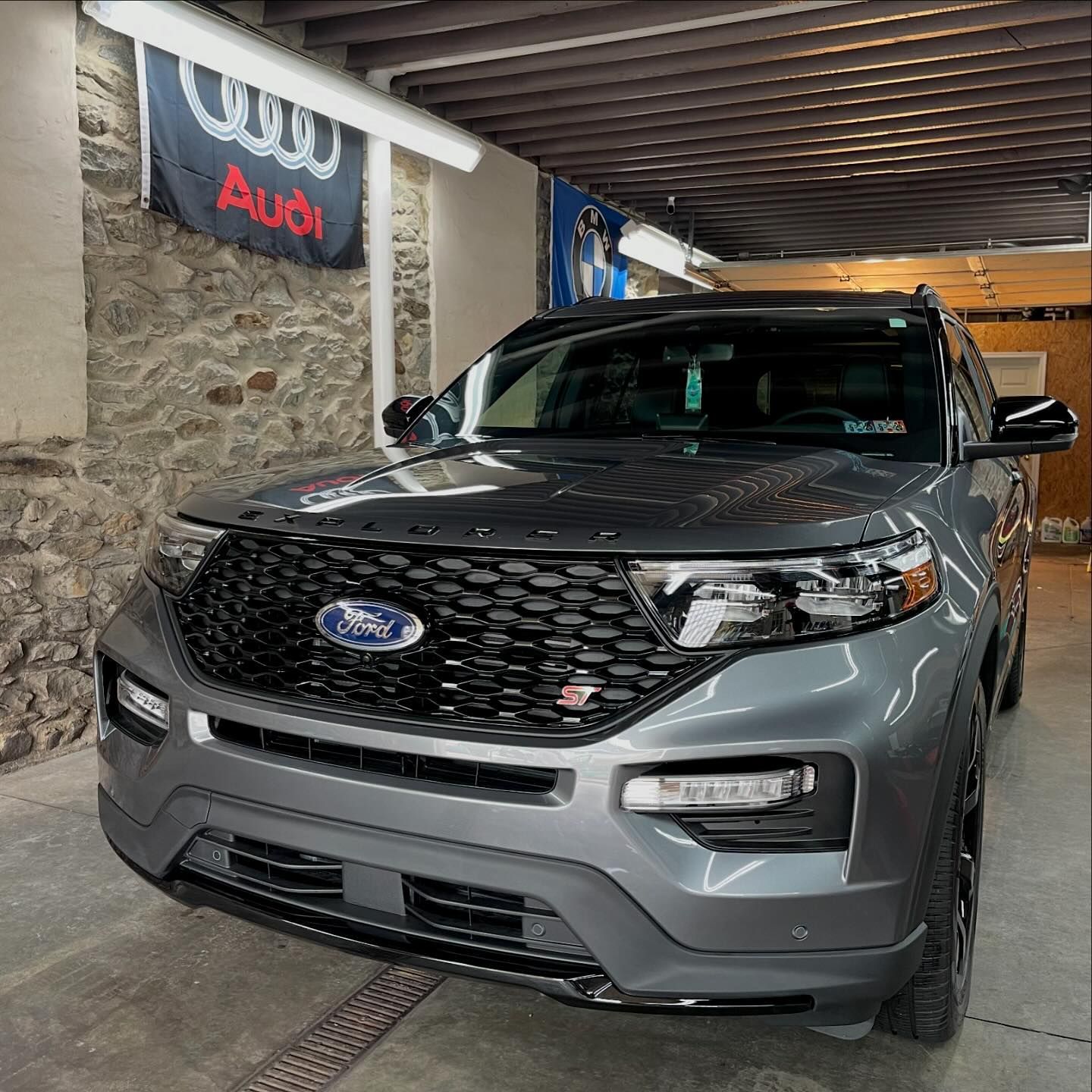 A ford explorer is parked in a garage next to an audi banner.