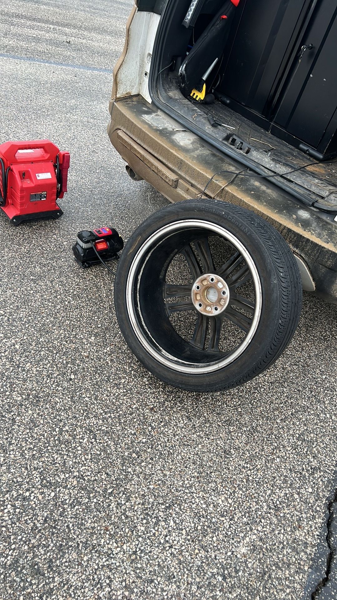 A tire is sitting on the ground next to a car.