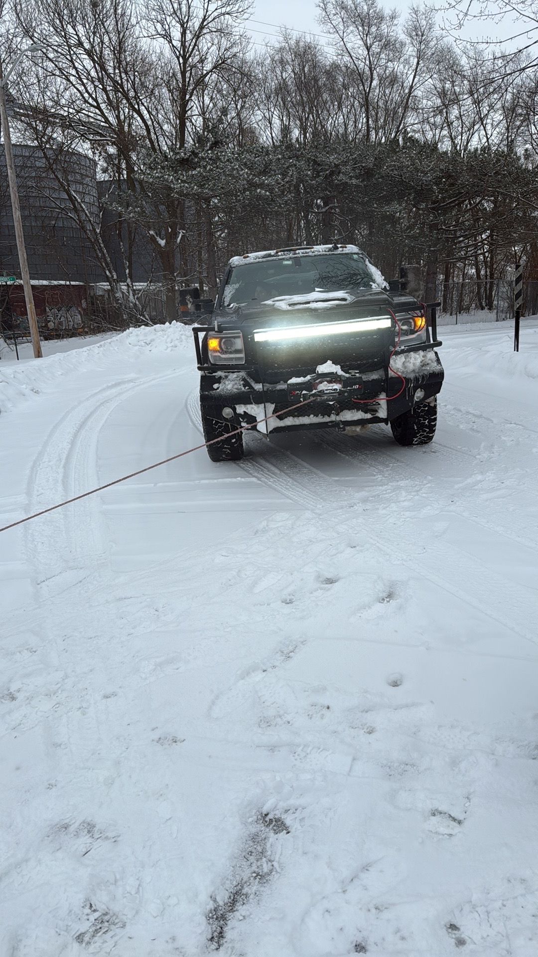A truck is driving down a snow covered road.
