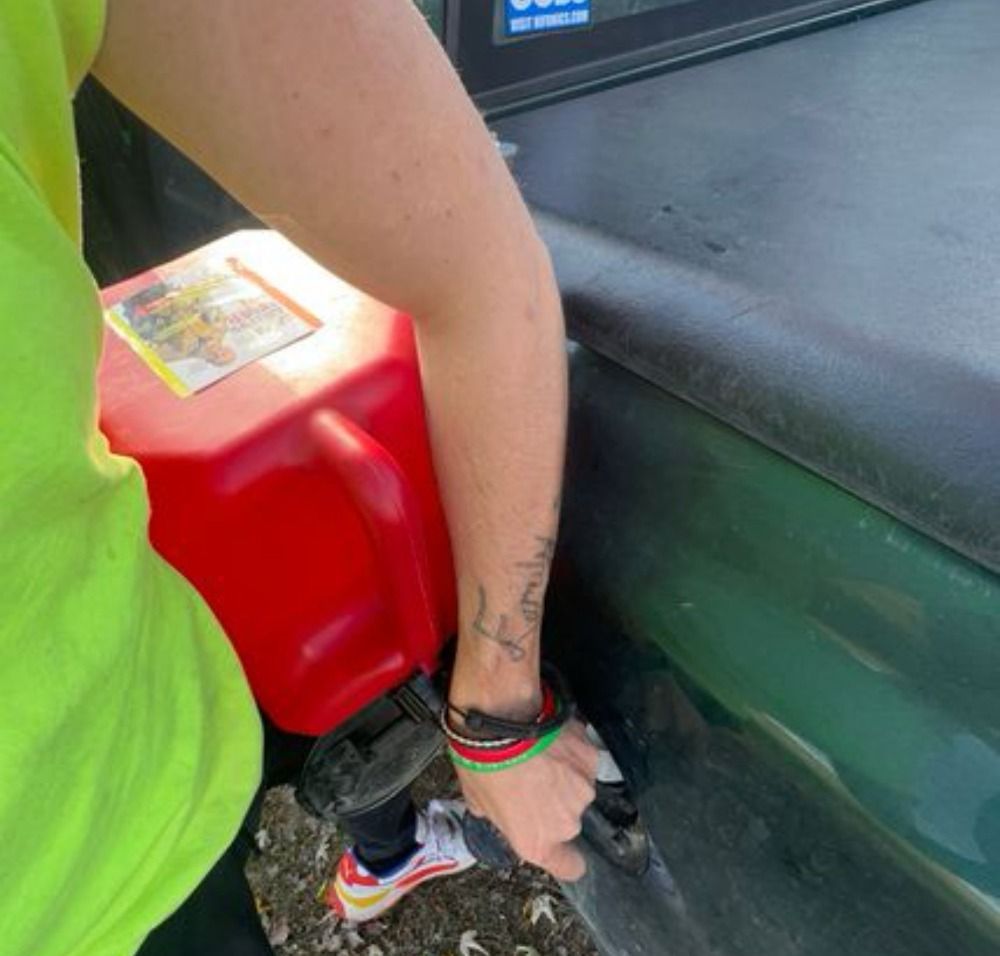 A woman is pumping gas into a green truck