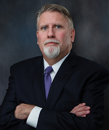 A man in a suit and tie with his arms crossed