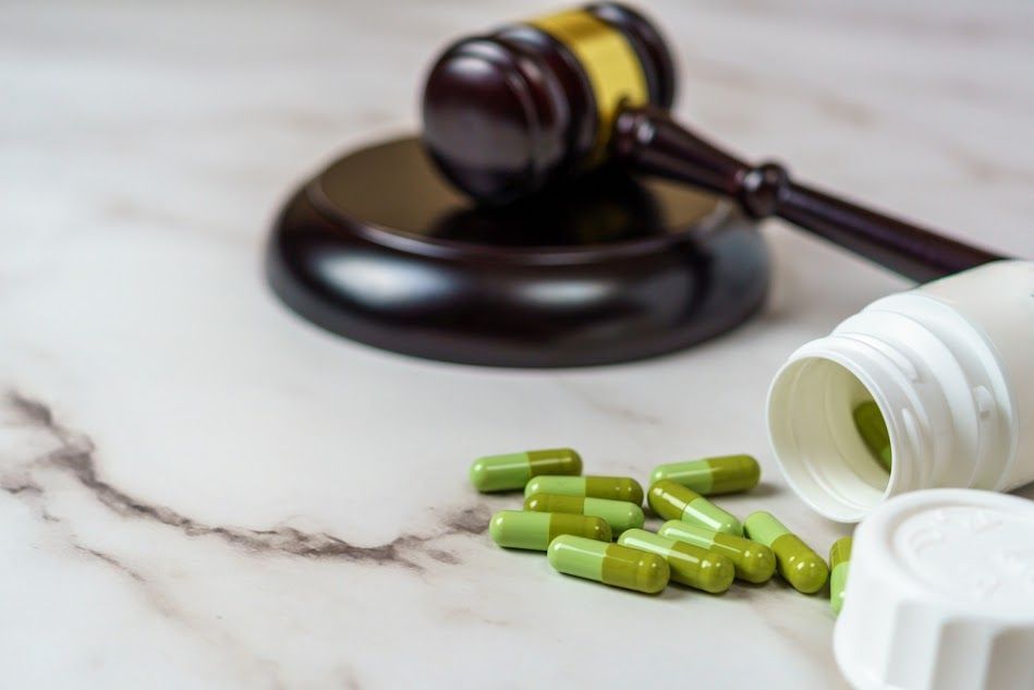 A judge 's gavel and a bottle of green pills on a table.